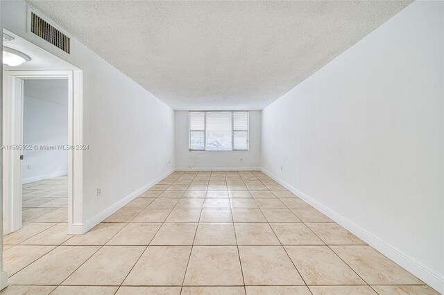 spare room with a textured ceiling and light tile flooring