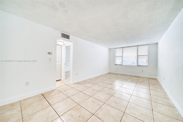 spare room featuring a textured ceiling and light tile floors