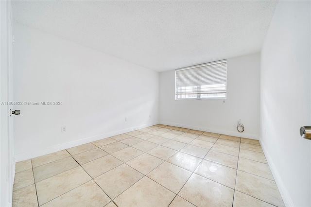 tiled empty room featuring a textured ceiling