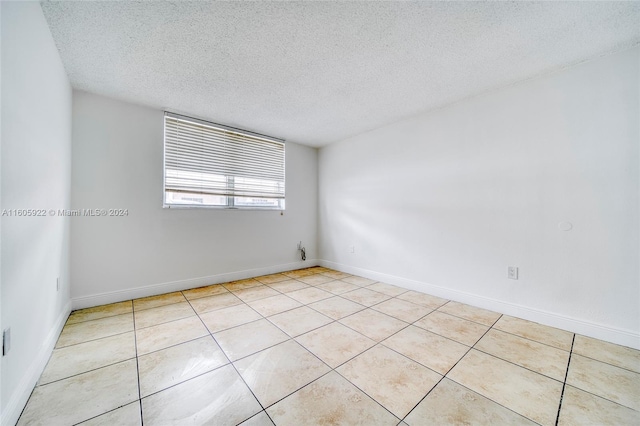 unfurnished room with light tile flooring and a textured ceiling