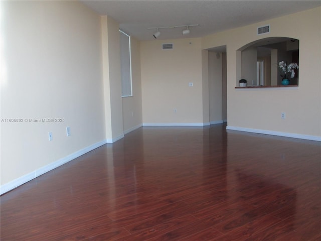 unfurnished room with dark wood-type flooring and track lighting