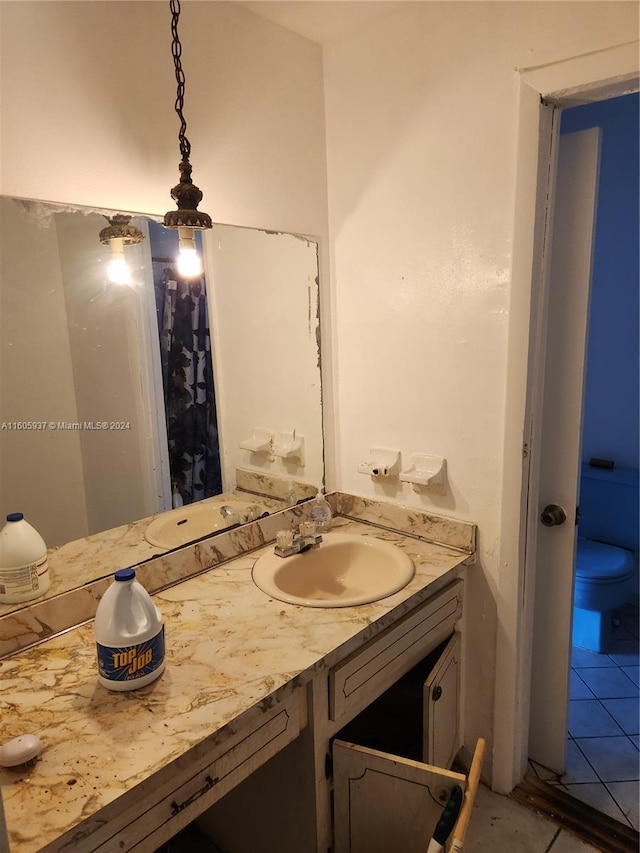 bathroom with tile flooring, vanity, and toilet