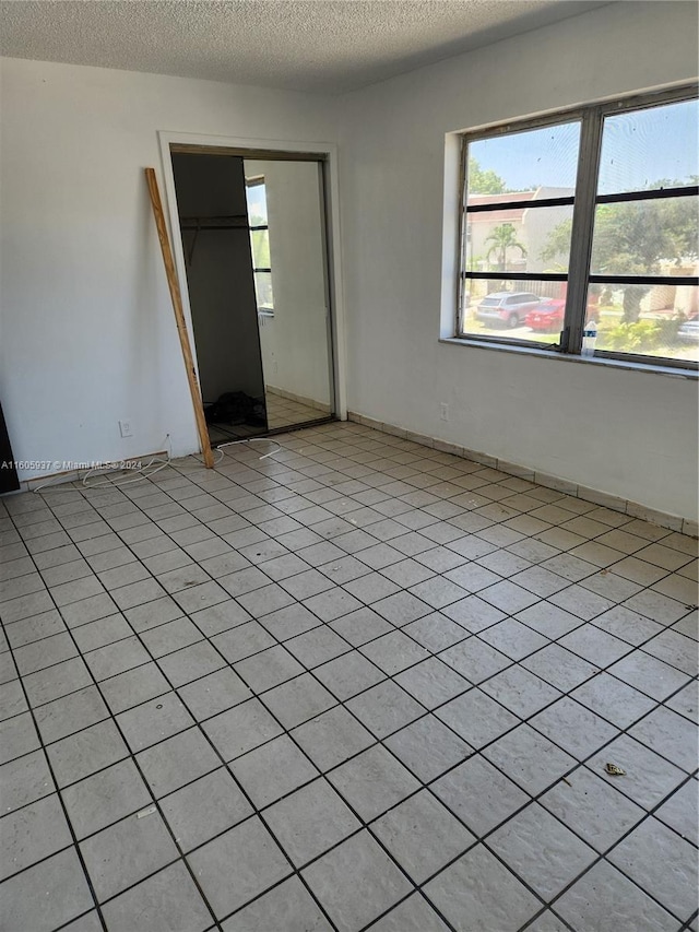 unfurnished room featuring a textured ceiling and light tile flooring