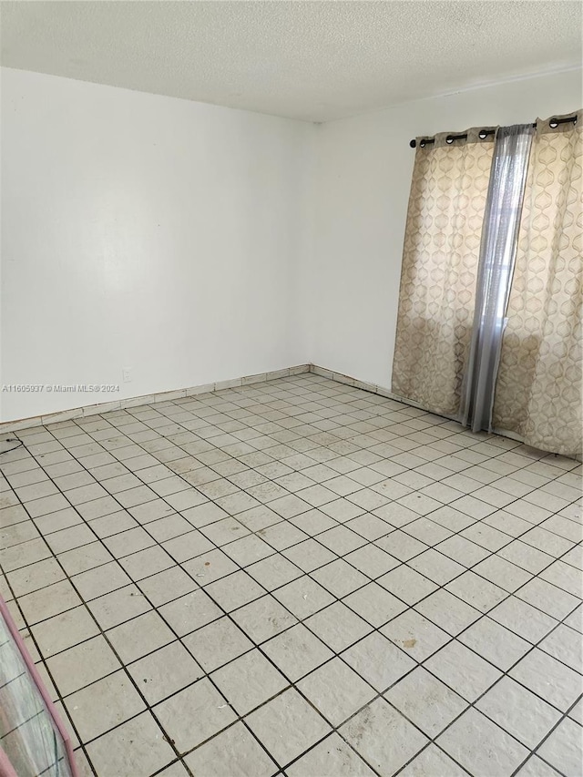 empty room with light tile flooring and a textured ceiling