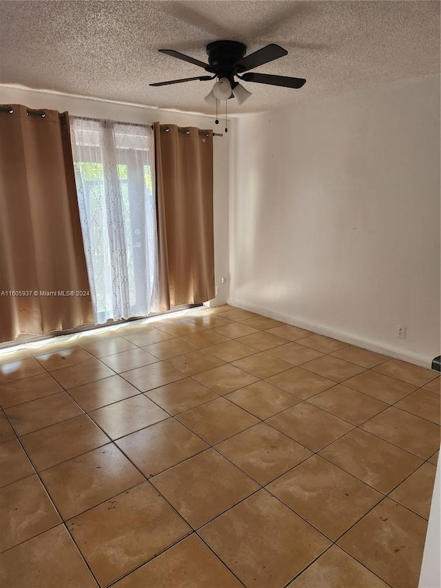 unfurnished room with tile flooring, ceiling fan, and a textured ceiling