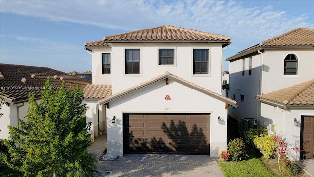 mediterranean / spanish-style house with a garage and central AC unit