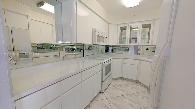 kitchen with white fridge with ice dispenser, light tile patterned floors, and white cabinetry