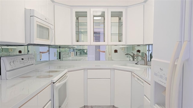 kitchen with white appliances, white cabinetry, and sink