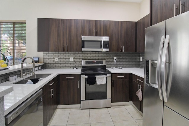 kitchen featuring light tile patterned floors, appliances with stainless steel finishes, decorative backsplash, dark brown cabinetry, and sink