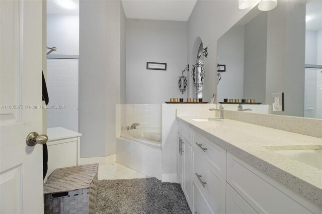 bathroom featuring dual vanity, tiled bath, and tile patterned floors