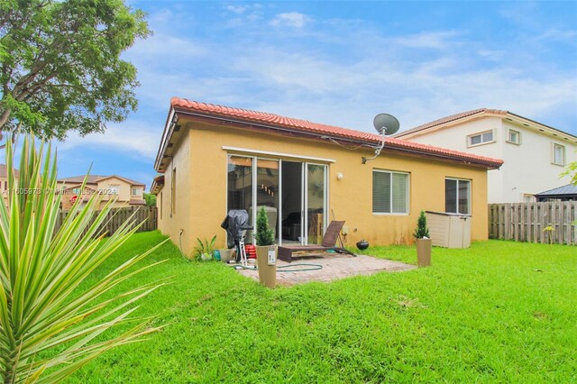 rear view of property with a patio and a lawn