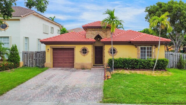 mediterranean / spanish house featuring a garage and a front yard