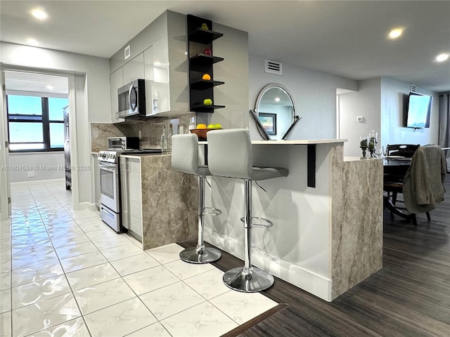 kitchen with stainless steel appliances, backsplash, and a breakfast bar