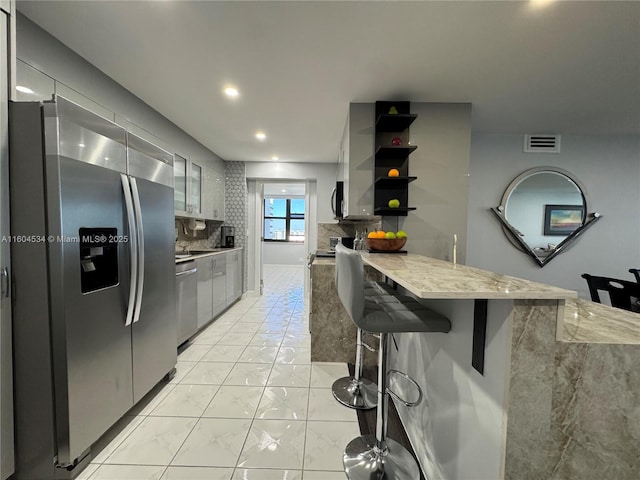 kitchen featuring a breakfast bar, stainless steel appliances, kitchen peninsula, and tasteful backsplash