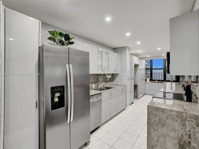 kitchen featuring sink, stainless steel appliances, light tile patterned floors, and white cabinetry