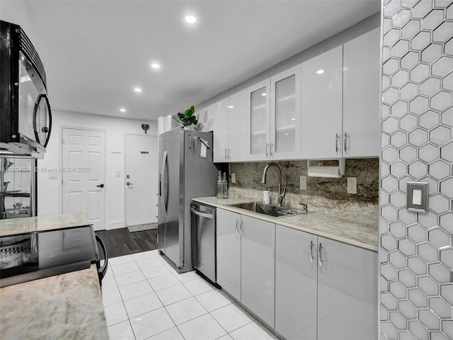 kitchen with light tile patterned floors, decorative backsplash, white cabinetry, appliances with stainless steel finishes, and sink