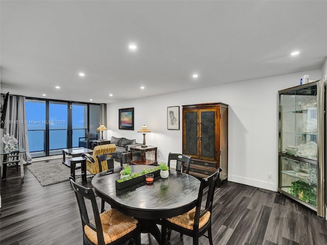 dining space with dark wood-type flooring, a wall of windows, and a water view