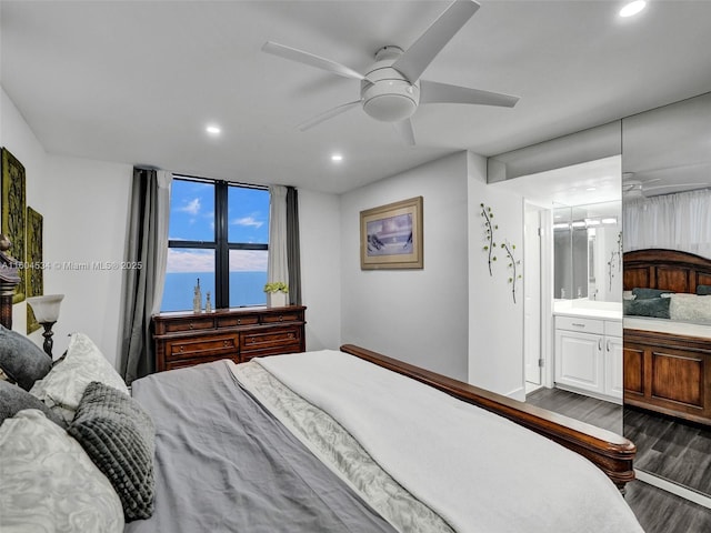 bedroom with ensuite bath, ceiling fan, dark hardwood / wood-style flooring, and a water view