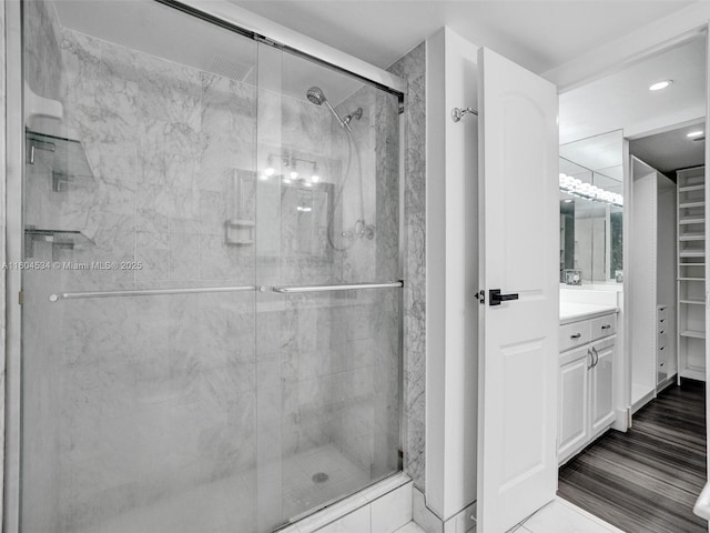 bathroom featuring a shower with shower door and vanity