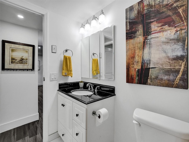 bathroom featuring wood-type flooring, vanity, and toilet