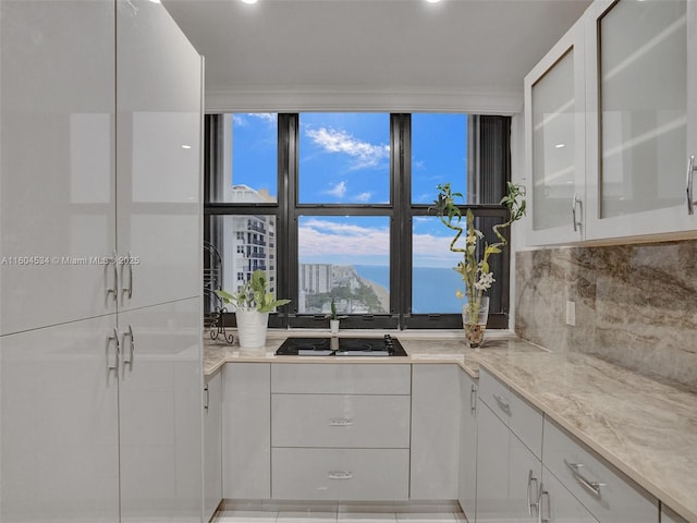 kitchen with light stone counters, white cabinets, and backsplash