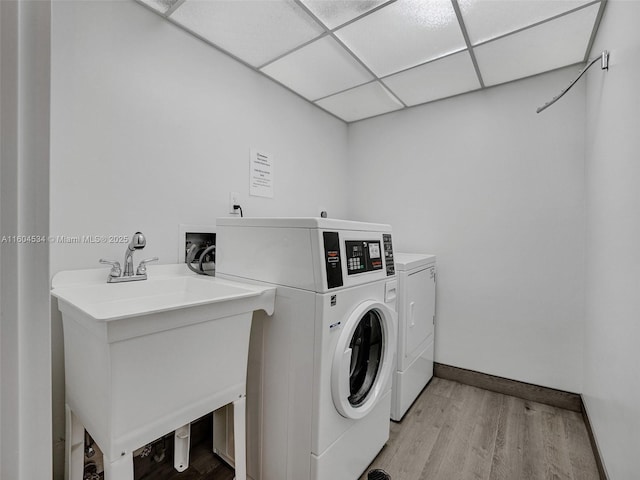 clothes washing area featuring sink, washer and clothes dryer, and light wood-type flooring