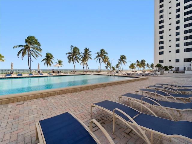 view of swimming pool featuring a water view and a patio