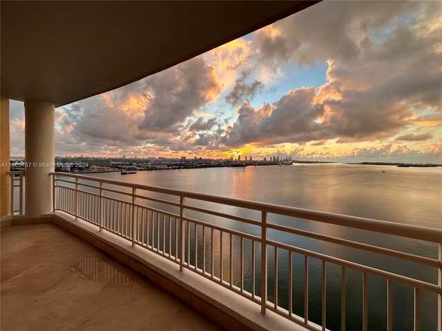 balcony at dusk featuring a water view