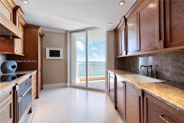 kitchen featuring light stone countertops, tasteful backsplash, sink, a water view, and oven