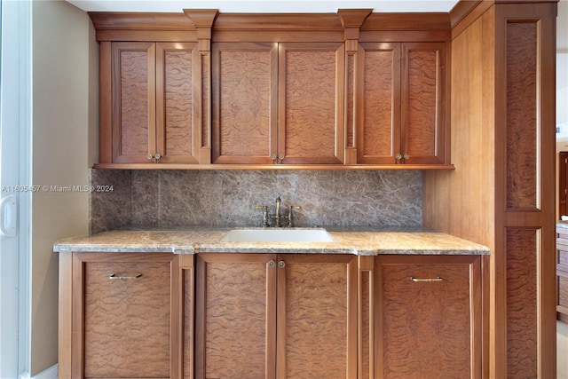 kitchen with light stone countertops, backsplash, and sink