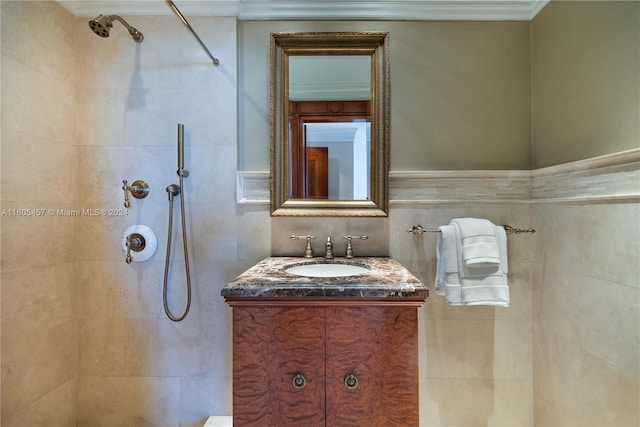 bathroom with a tile shower, crown molding, vanity, and tile walls