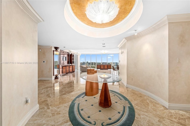 hallway featuring a notable chandelier, crown molding, a raised ceiling, and baseboards