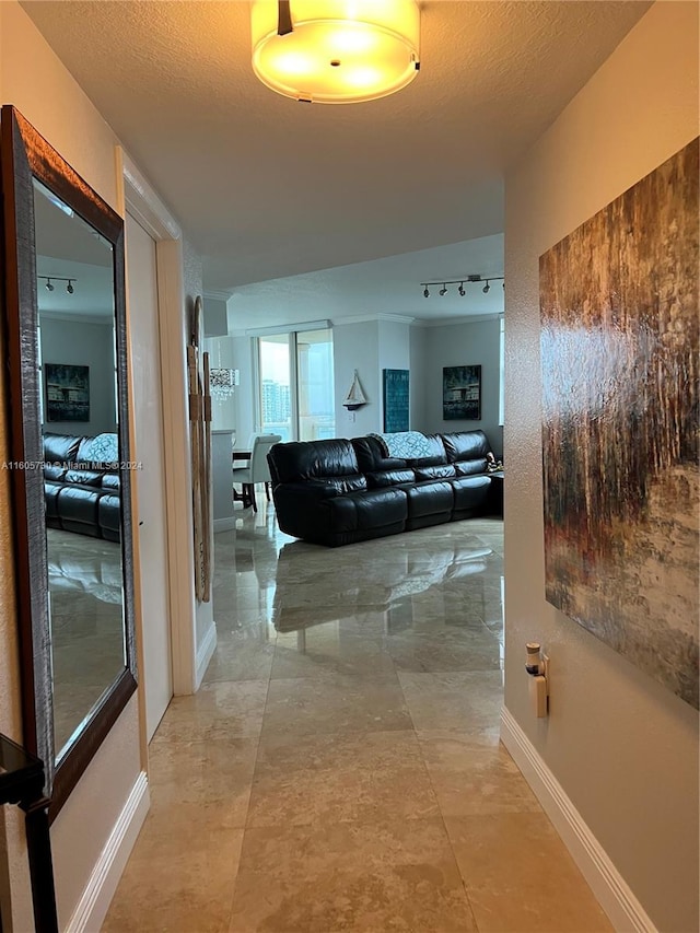 corridor featuring a textured ceiling, track lighting, and light tile floors