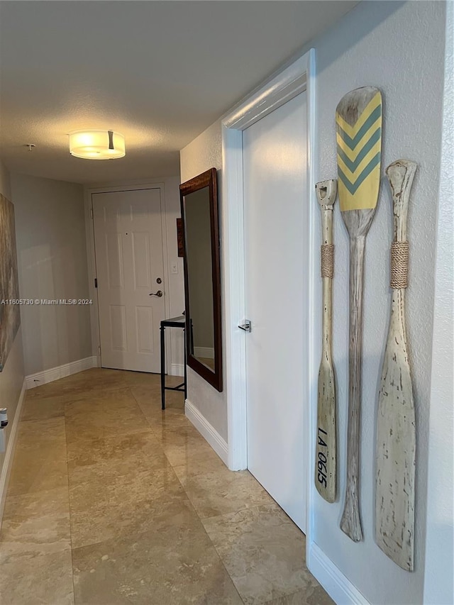 hall featuring a textured ceiling and light tile floors