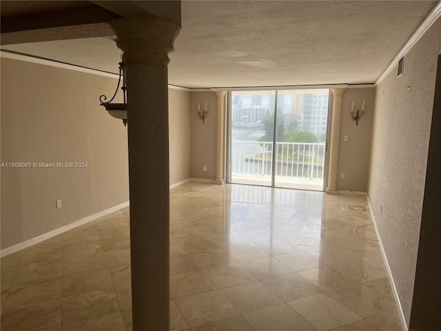 unfurnished room featuring tile patterned floors, floor to ceiling windows, ornate columns, and ornamental molding