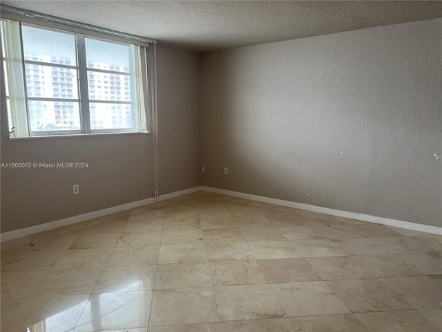 tiled spare room with a textured ceiling