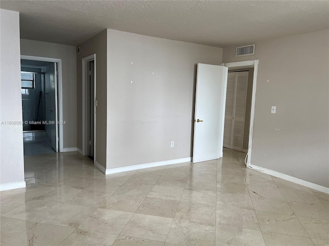 tiled empty room featuring a textured ceiling