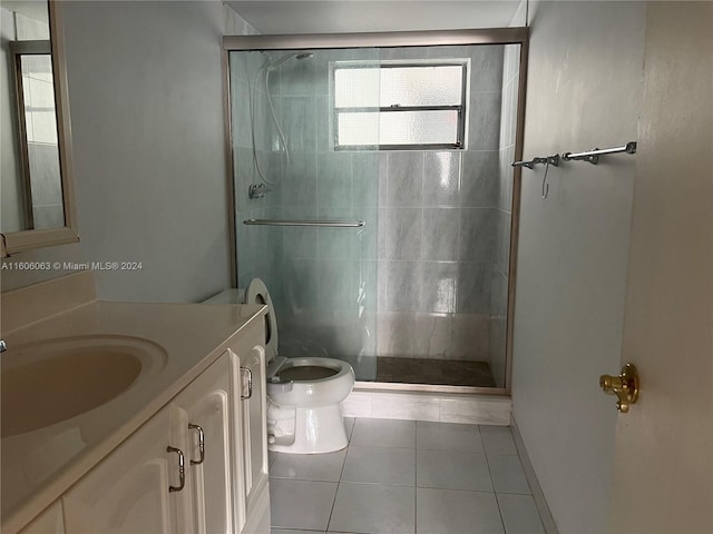 bathroom featuring vanity, toilet, tile patterned floors, and a shower with door