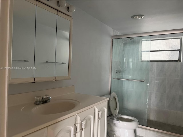 bathroom featuring a shower with shower door, toilet, and vanity