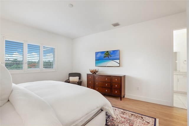 bedroom with ensuite bathroom and light wood-type flooring