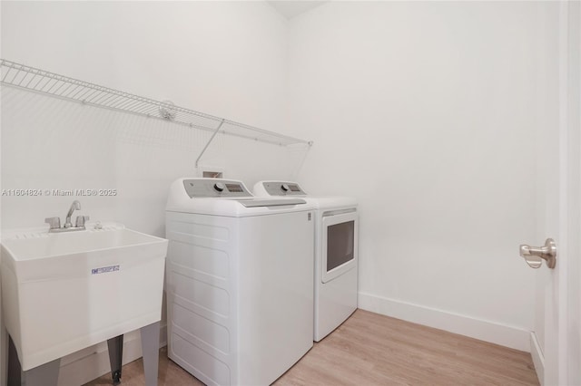 washroom with light wood-type flooring, independent washer and dryer, and sink