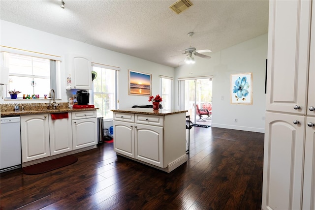 kitchen with white cabinets, a center island, dark hardwood / wood-style flooring, and dishwasher