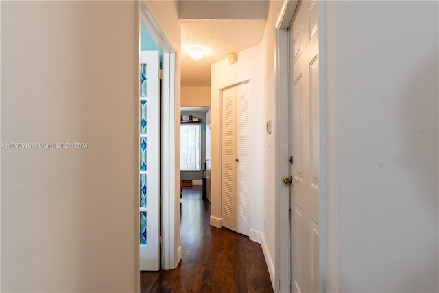 corridor featuring dark wood-type flooring and a textured ceiling