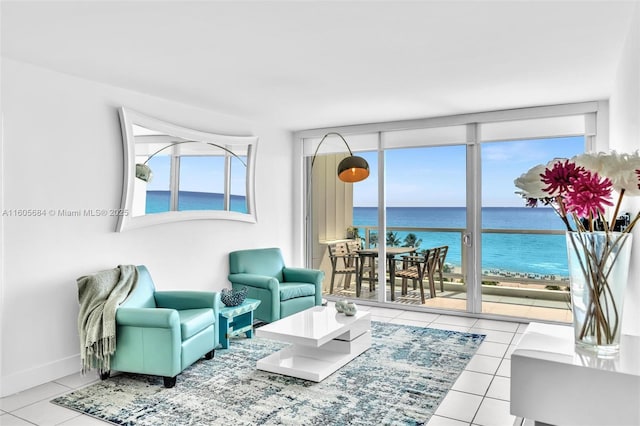 tiled living area featuring baseboards, a water view, and floor to ceiling windows