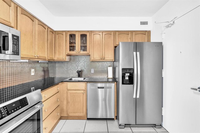 kitchen featuring backsplash, appliances with stainless steel finishes, light tile patterned flooring, and sink