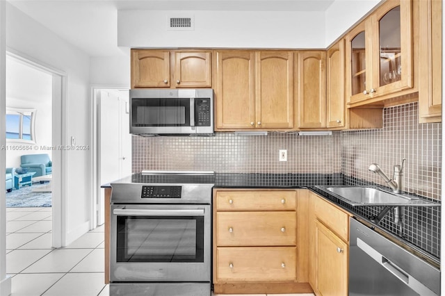 kitchen featuring backsplash, sink, light tile patterned floors, and stainless steel appliances