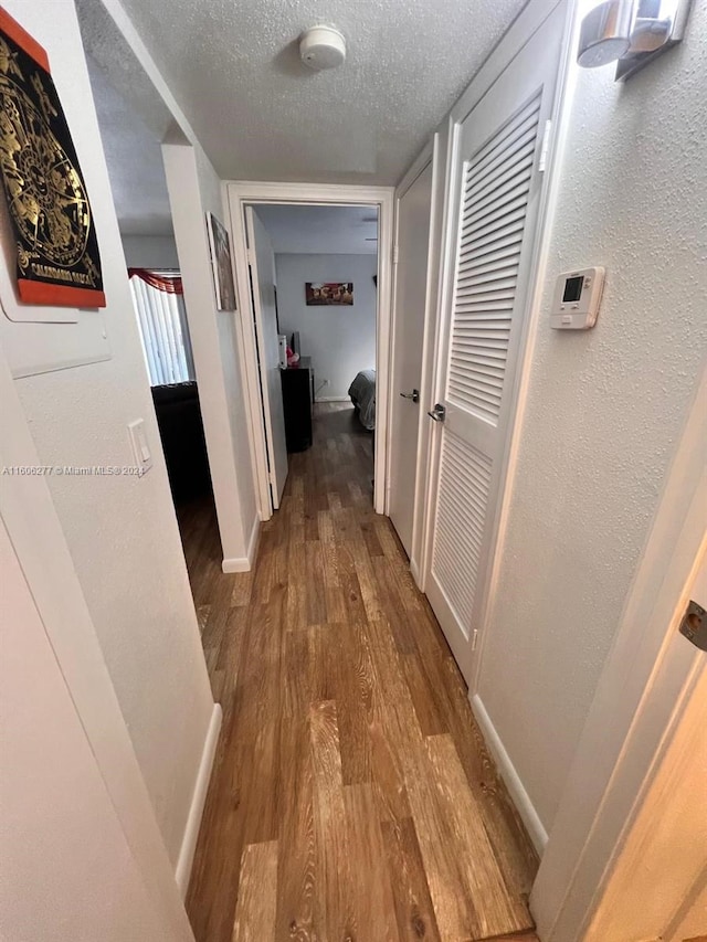 hallway featuring hardwood / wood-style flooring and a textured ceiling