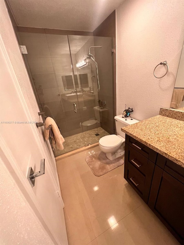 bathroom featuring tile flooring, a textured ceiling, an enclosed shower, vanity, and toilet