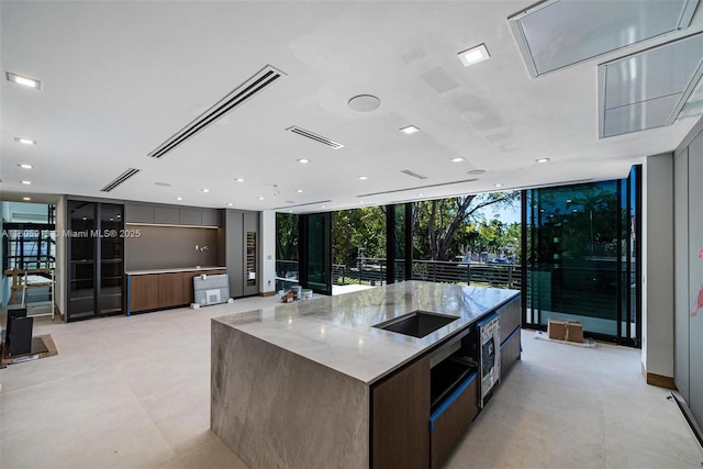 kitchen featuring a large island, floor to ceiling windows, and light stone counters