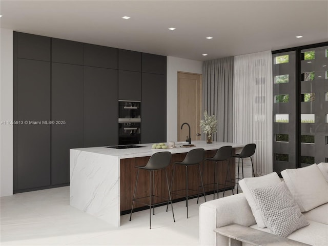 kitchen featuring a large island with sink, floor to ceiling windows, a kitchen breakfast bar, and black appliances